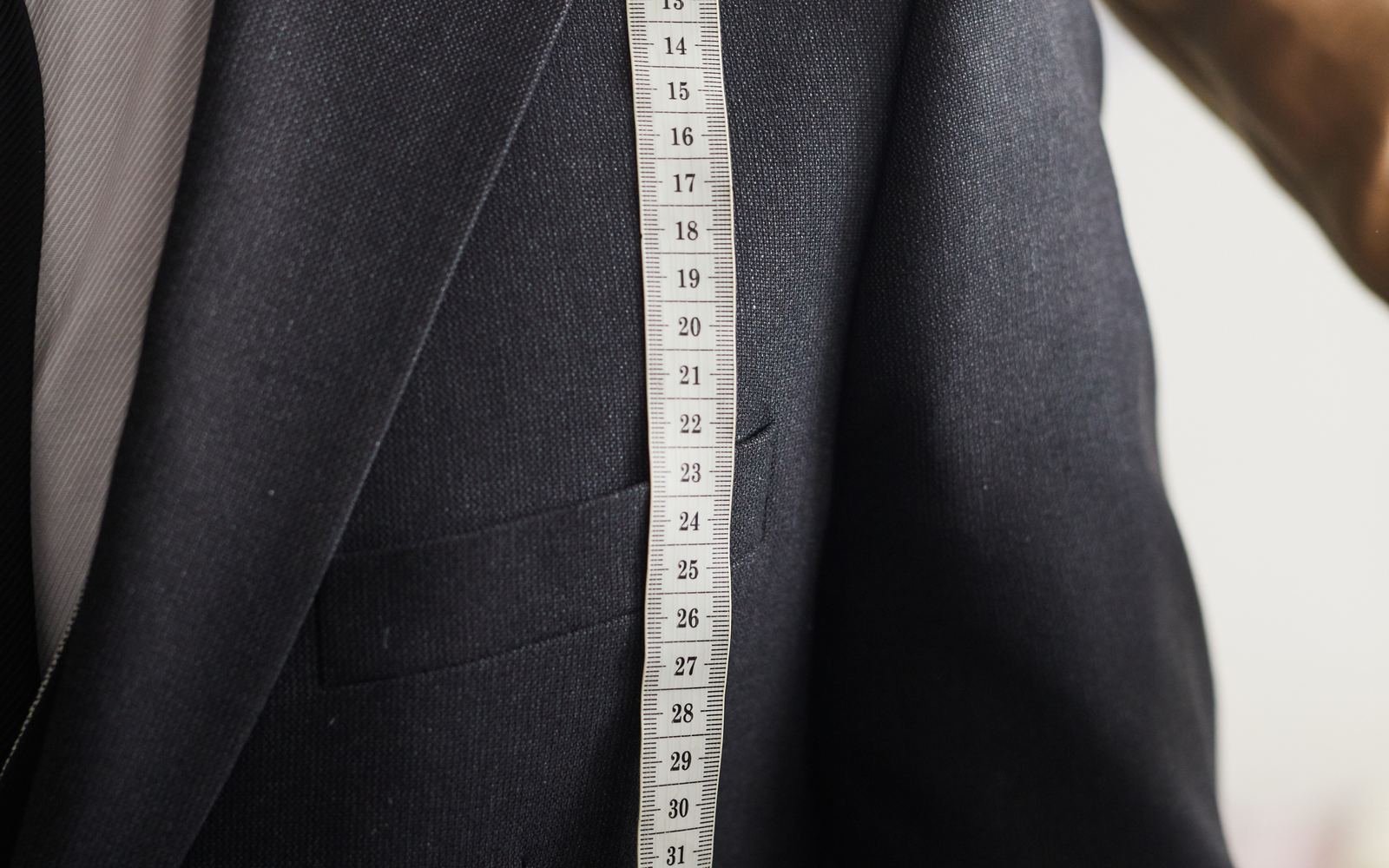 A tailor measuring a dark suit